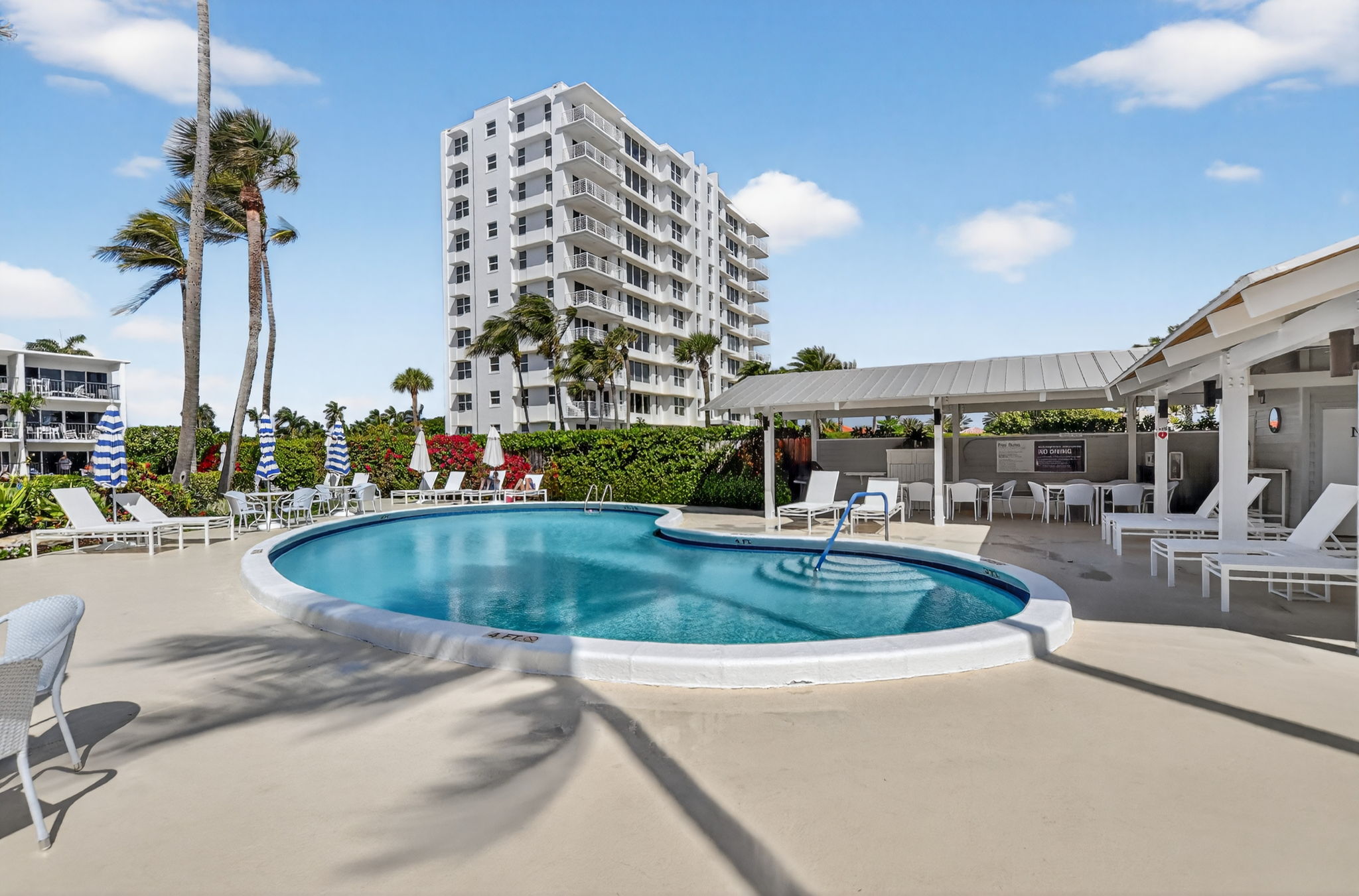 Shared condo pool with lounge chairs and cabana
